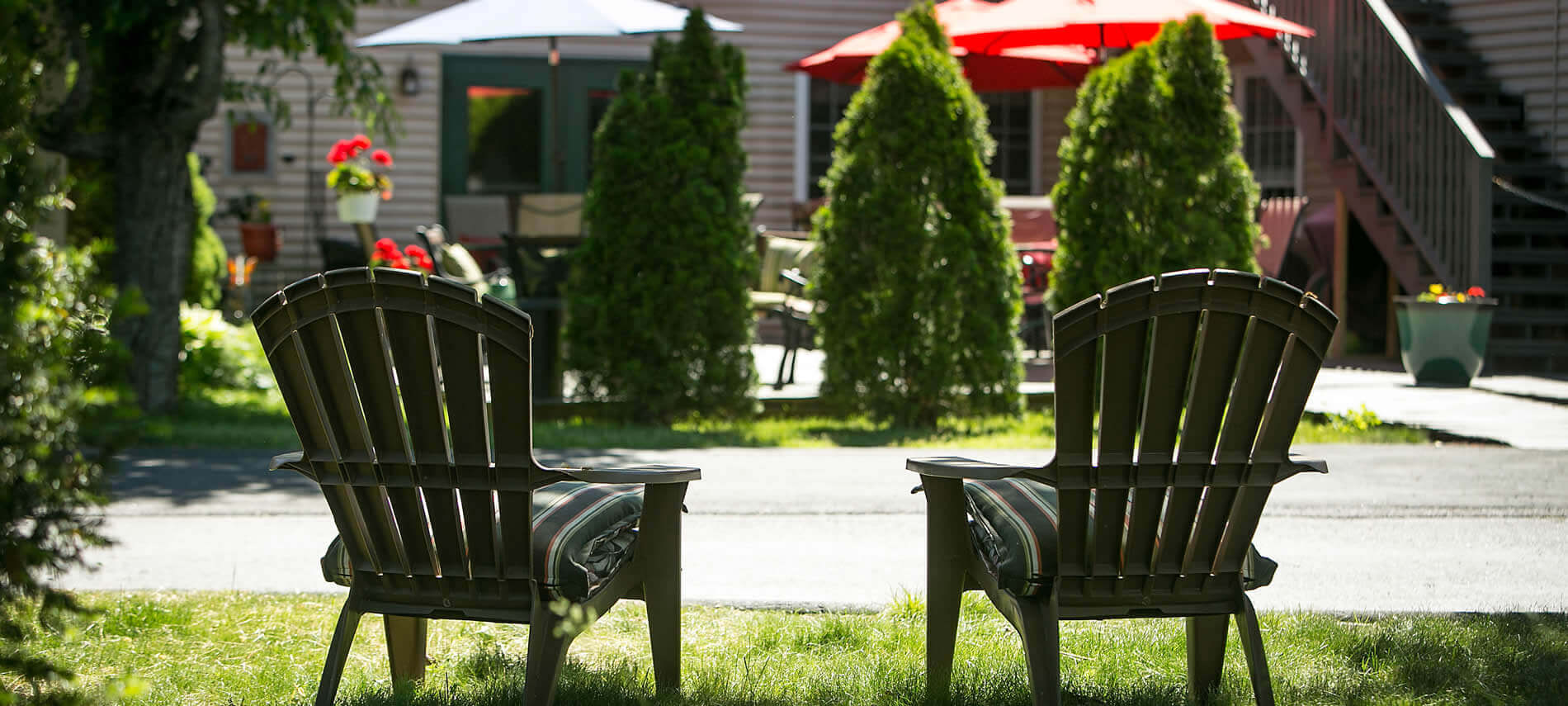 Two Adirondack chairs with green striped cushions sitting on grass